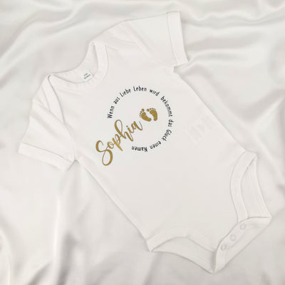 weißer Babybody bedruckt mit Namen und dem Spruch "Wenn aus Liebe Leben wird bekommt das Glück einen Namen"