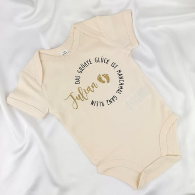 naturfarbener Babybody bedruckt mit Namen und dem Text "Das größte Glück ist manchmal ganz klein"